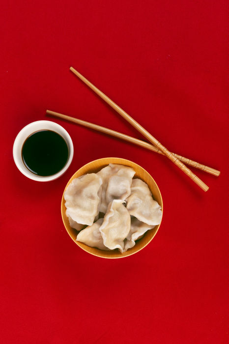 flatlay-with-dumplings-and-chopsticks-on-red-background